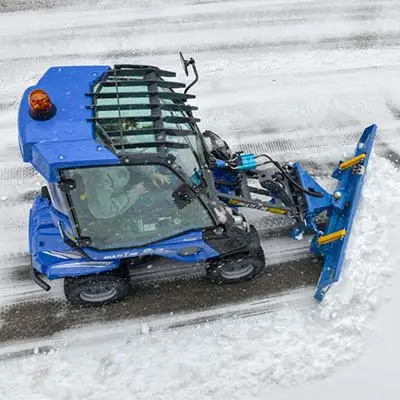 Pienkuormaaja MultiOne 2.3 hytillä työntää lunta.